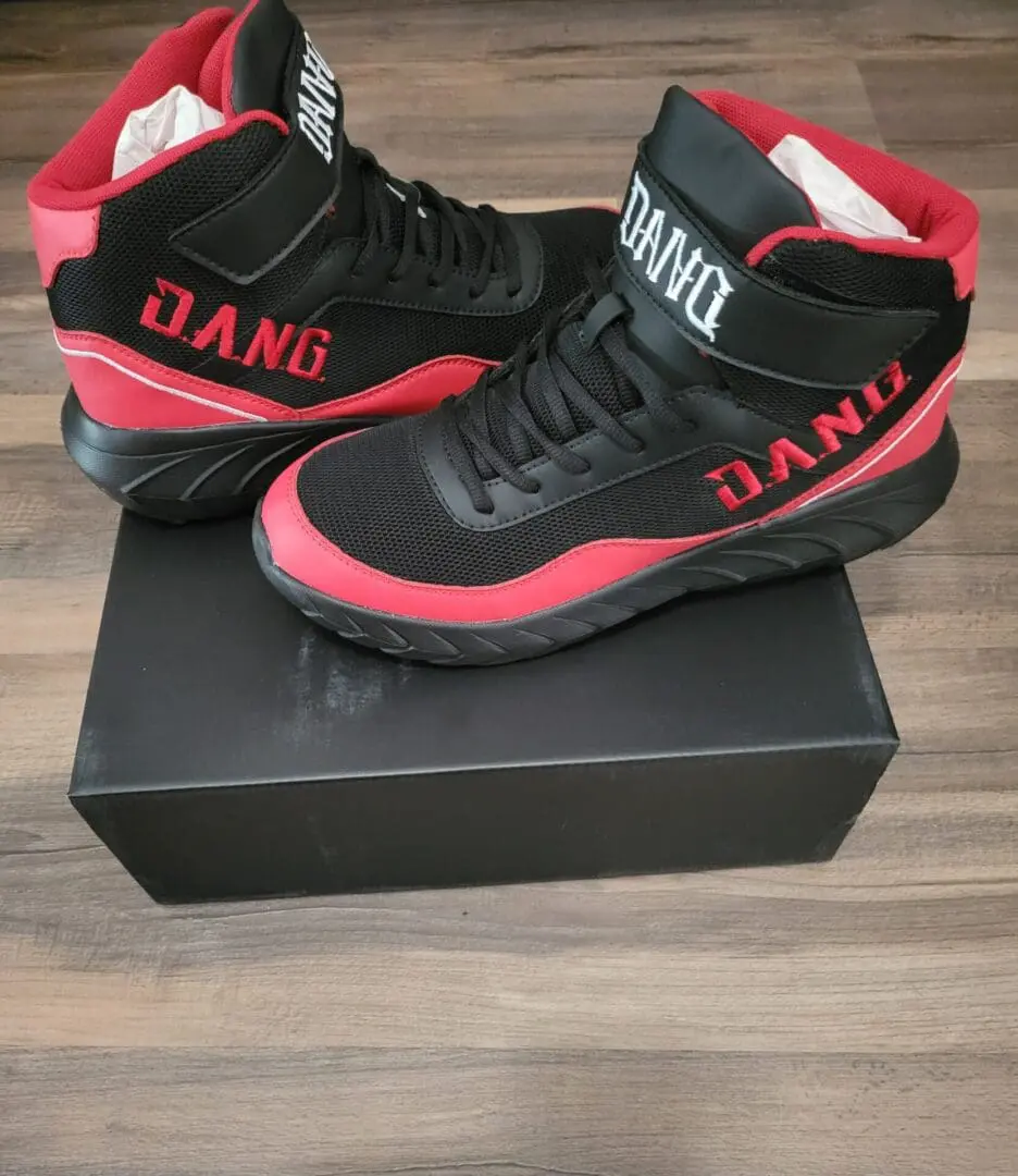 Black and red DANG high-top sneakers on a black box.